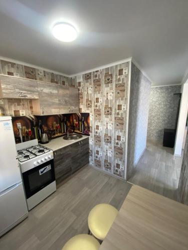 a kitchen with a stove and a sink and a refrigerator at PALITRA in Petropavlovsk