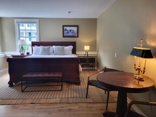 a bedroom with a large bed and a table at The Stowe Village Inn in Stowe