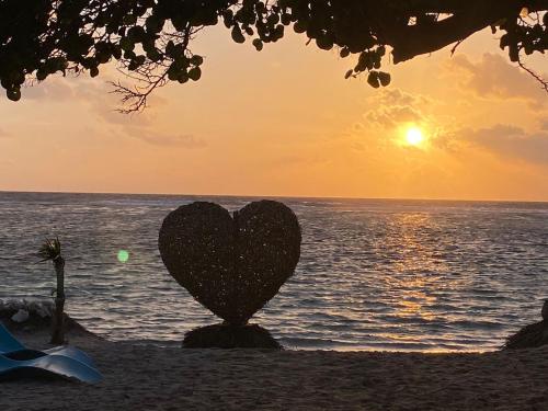 a heart statue on the beach with the sunset at Cabanas ecoturisticas Costa Maya in Mahahual