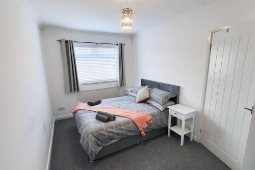 a small bedroom with a bed with a window at Lovely & modern 2-Bedroom Flat above shop in Tonteg in Llantwit Fardre