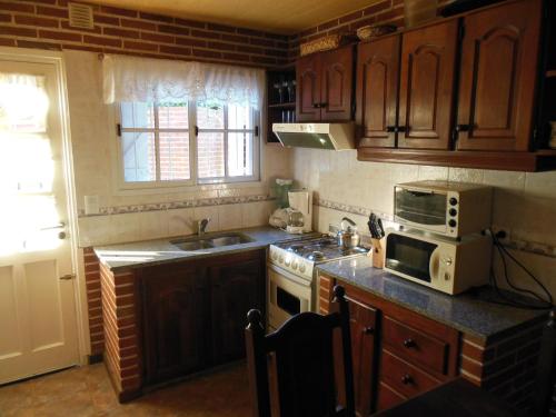 a kitchen with a microwave and a stove top oven at Cabañas Valeria Kaupe in Valeria del Mar