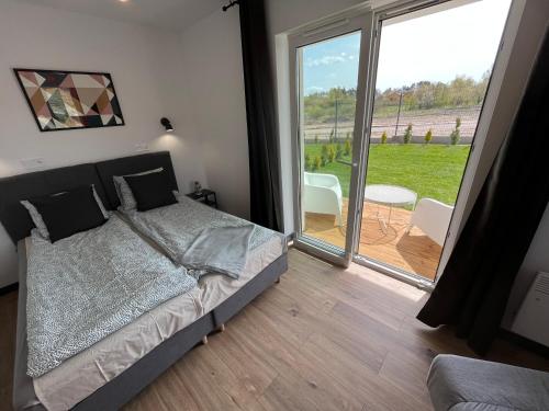 a bedroom with a bed and a large window at Apartamenty Dębina 300m do plaży in Debina