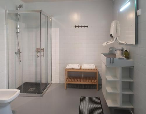 een witte badkamer met een douche en een wastafel bij Les gîtes de la Madeleine in La Chapelle-sur-Loire
