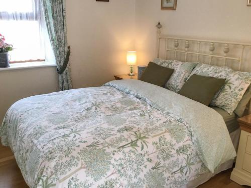 a bedroom with a bed with a floral bedspread at Whitney Cottage in Broadway