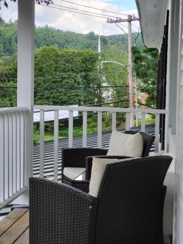 a porch with wicker chairs and a view of the forest at The Stowe Village Inn in Stowe