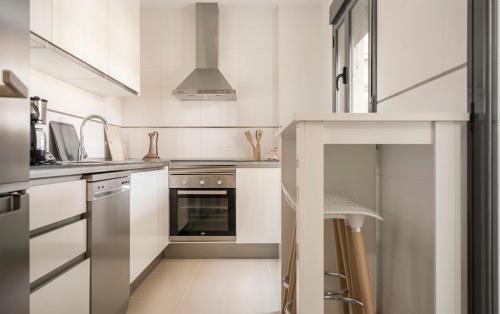 uma cozinha com armários brancos e um forno com placa de fogão em Atico Duplex en Playa Serena em Roquetas de Mar