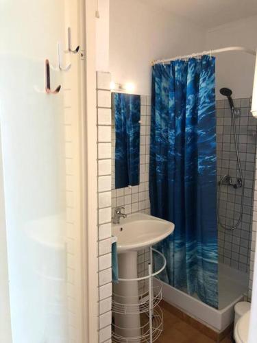 La salle de bains est pourvue d'un lavabo et d'un rideau de douche bleu. dans l'établissement Studio Mer et Vacances, à Sausset-les-Pins
