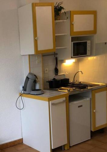 une petite cuisine avec des armoires blanches et un évier dans l'établissement Studio Mer et Vacances, à Sausset-les-Pins