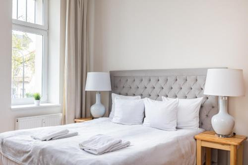 a bedroom with a bed with white sheets and two lamps at Apartamenty Vincent Sopot in Sopot