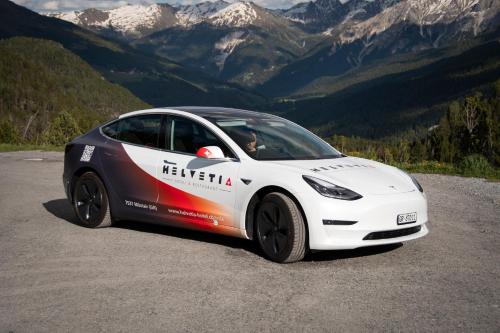 a white tesla car parked on the side of a mountain at Hotel Helvetia in Müstair