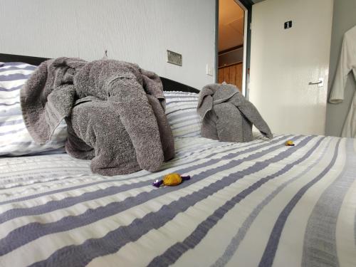 two stuffed elephants laying on top of a bed at Dan's House in Manchester