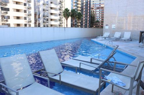 a group of chairs sitting in a swimming pool at Flat Premium Particular Cullinan Hotel in Brasilia