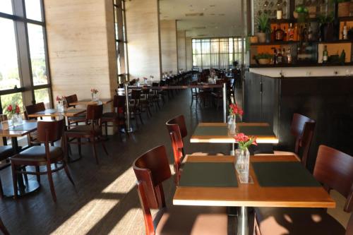 a restaurant with wooden tables and chairs and windows at Flat Premium Particular Cullinan Hotel in Brasilia