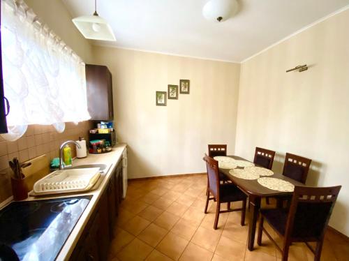 uma cozinha com uma mesa e cadeiras e um lavatório em Przy Dębach em Stargard