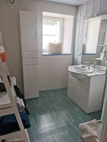 une salle de bain blanche avec un lavabo et un miroir dans l'établissement Maison de village brocante, à Coucouron