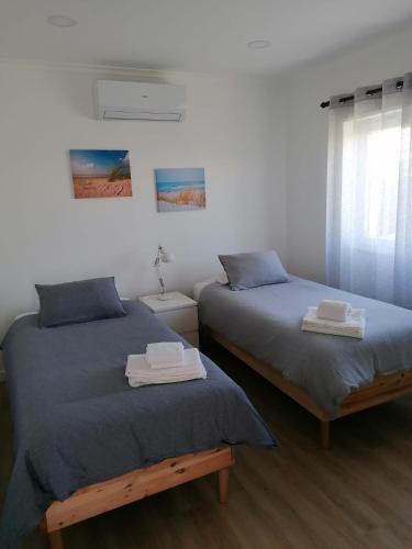 1 dormitorio con 2 camas con sábanas azules y ventana en Baleal Atlantic Villa en Baleal