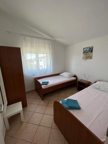 Habitación pequeña con 2 camas y ventana en Apartments Duda, en Vir