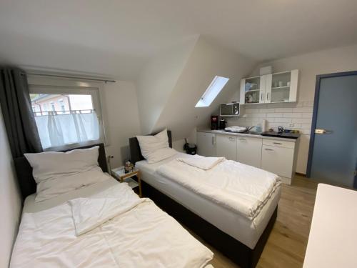 two beds in a small room with a kitchen at Apartment Q im Zentrum von Königsbronn Monteurzimmer in Königsbronn
