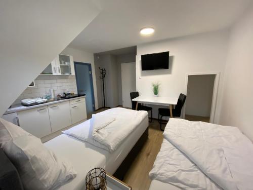 a room with two beds and a kitchen with a table at Apartment Q im Zentrum von Königsbronn in Königsbronn