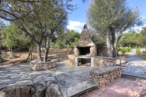 una chimenea de piedra en un patio con árboles en MaryLou by DomusAway, en Monte Petrosu