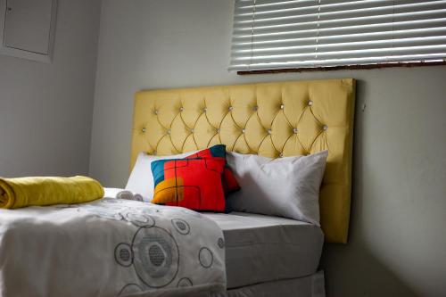 a bed with a yellow headboard and some pillows at 66 Anglers in Richards Bay
