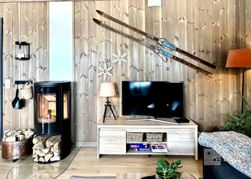 een woonkamer met een tv aan een houten muur bij New apartment Hafjelltoppen ski inout in Hafjell
