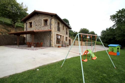 a yard with a playground with a house at Los cerezos in Bárcena de Cicero