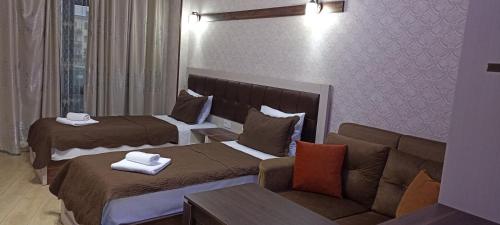 a hotel room with two beds and a couch at EMEG Hotel and Restaurant in Batumi