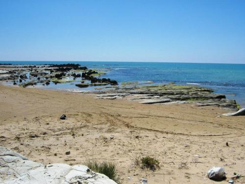 a sandy beach with rocks in the water at Punta Grande - Scala dei Turchi in Realmonte