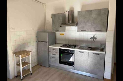 Appartamento a Monfalcone, con parcheggio gratuito في مونفالكوني: مطبخ مع أجهزة ستانلس ستيل وموقد