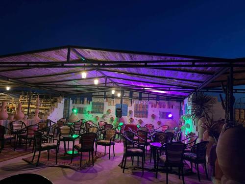 un groupe de tables et de chaises avec des lumières violettes dans l'établissement Welcome Meridiana Resort - Families and Couples Only, à Djerba