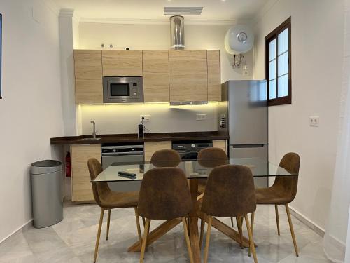 uma cozinha com uma mesa de vidro e 4 cadeiras em MonKeys Apartments Santa Clara Deluxe em Sevilha