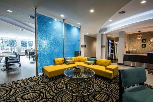 a living room with a yellow couch and a table at Comfort Suites Fort Lauderdale Airport South & Cruise Port in Dania Beach