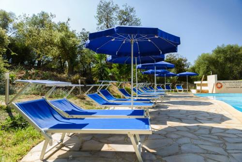 una fila de sillas y sombrillas azules junto a una piscina en Résidence Itylon, en Cargèse