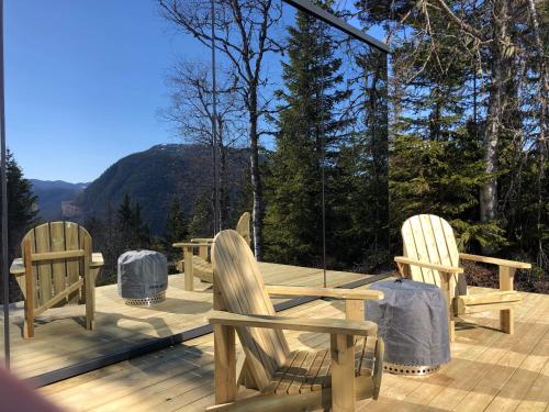 three wooden chairs and a table on a deck at Vidsyn Midjås in Vistad