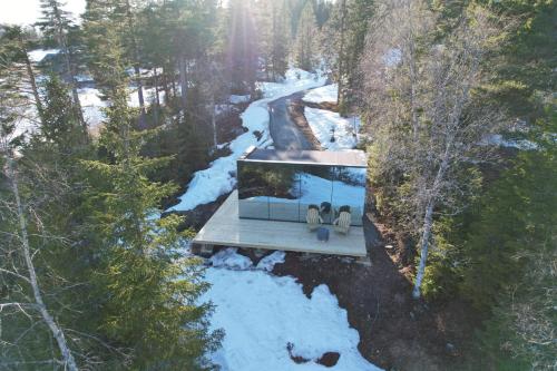 two people sitting on a glass house in the woods at Vidsyn Midjås in Vistad