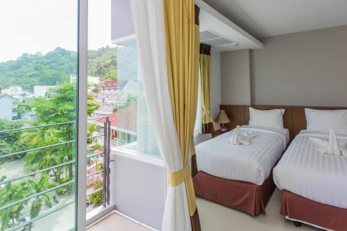 a bedroom with two beds and a balcony at Baan Lukkan Patong Resort in Patong Beach