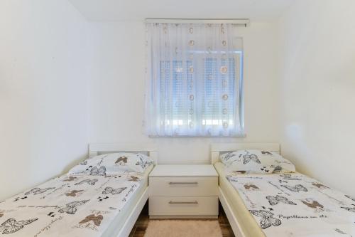 2 łóżka pojedyncze w sypialni z oknem w obiekcie Apartment South w mieście Zadar