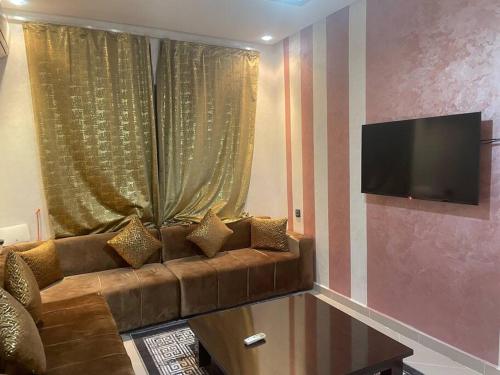a living room with a brown couch and a flat screen tv at LH résidence mezouar1 appartement 4 in Laayoune