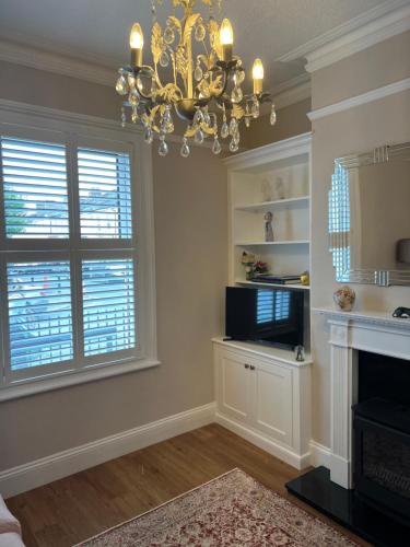 a living room with a chandelier and a fireplace at The Lily Pad - Boutique Townhouse, a short walk to Town Center and Racecourse in Cheltenham