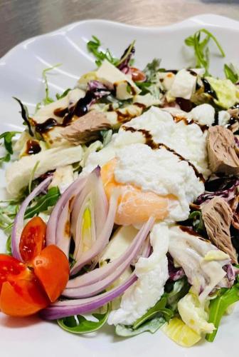 a white plate with a salad with meat and vegetables at Hotel Villaggio Ristorante Pizzeria Museo TANIT in Carbonia