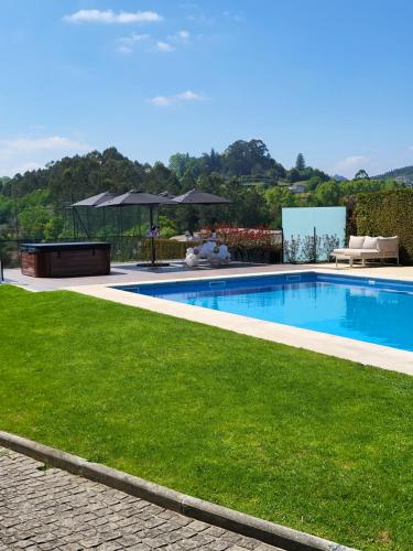 a swimming pool in a yard with a green lawn at Villa Moura - Pool & Jacuzzi in Póvoa de Lanhoso