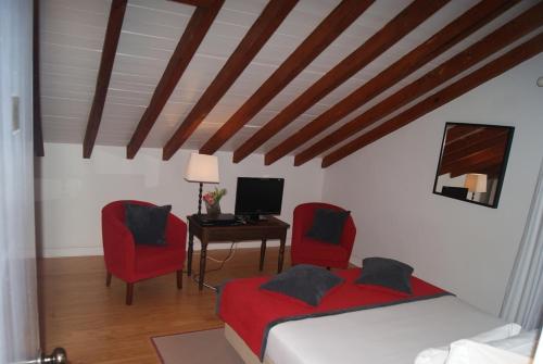 a bedroom with two red chairs and a desk with a computer at Casa do Comendador in São Roque do Pico