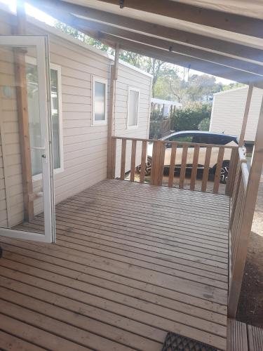 eine Veranda mit einer Holzterrasse und einer Glasschiebetür in der Unterkunft Mobil-home premium 325 in Narbonne
