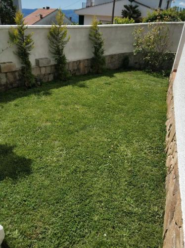 a yard with green grass and a retaining wall at La lechuza blanca in Casavieja
