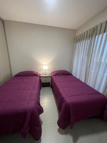 dwa łóżka w sypialni z fioletową pościelą i lampką w obiekcie La Victoria w mieście Lujan de Cuyo