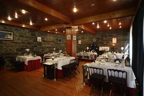a dining room with white tables and chairs and a brick wall at Quinta de São Domingos house in Peso da Régua