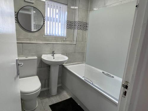 a bathroom with a sink and a toilet and a bath tub at NEW! 4 Bedroom London House with Garden and Lawn in London