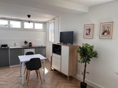 ein Wohnzimmer mit einem Tisch und einem TV sowie eine Küche in der Unterkunft studio trankil coeur d'Ancenis - balcons d'Ancenis in Ancenis