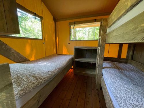 Ce dortoir comprend 2 lits superposés et 2 fenêtres. dans l'établissement Lodges du Bois Dodo - ancien Camping de Bois Redon, à Septfonds
